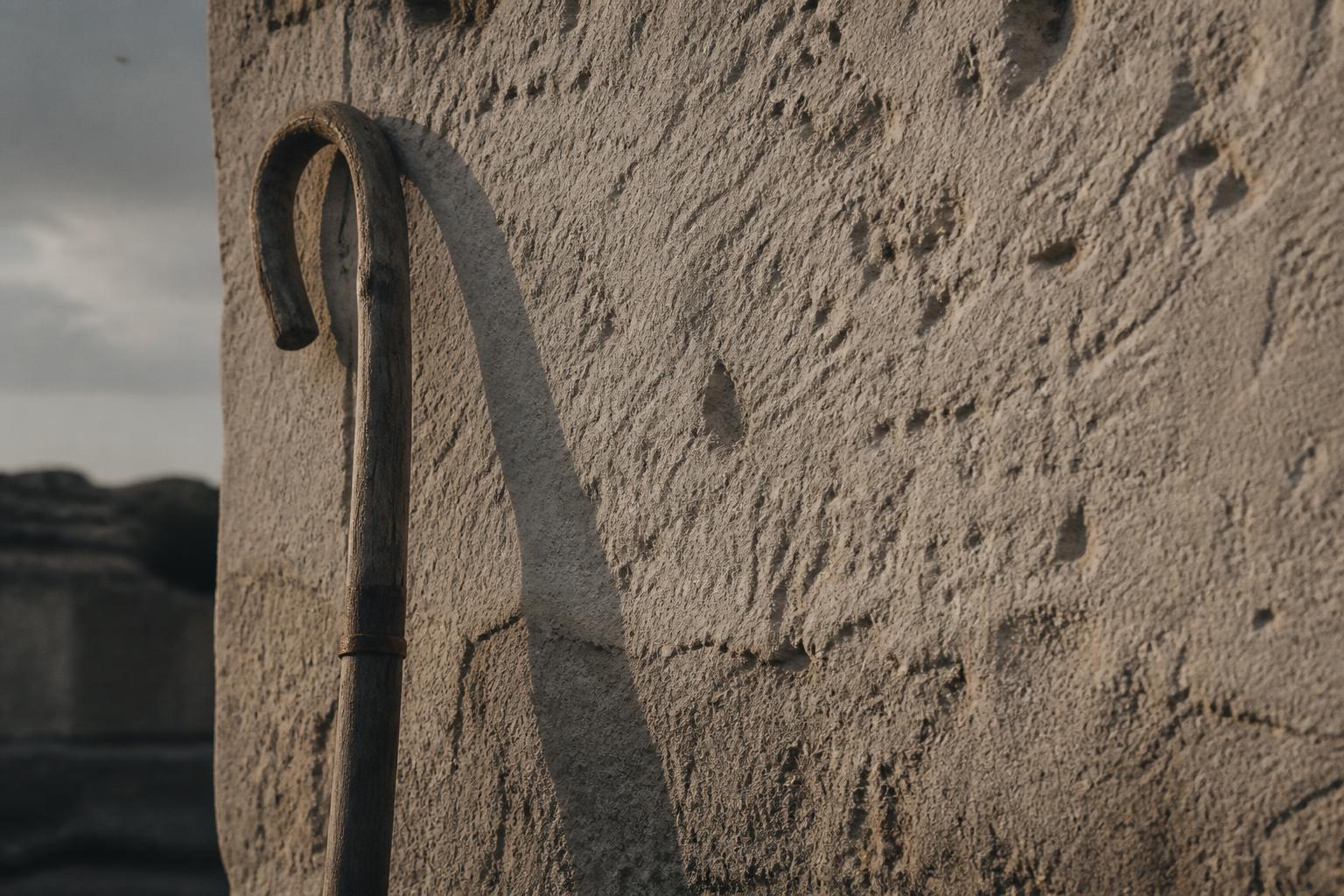 Weathered shepherd's crook against limestone